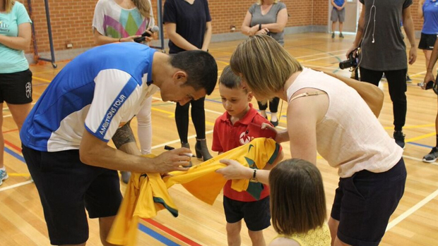 Tim Cahill signs a jersey for a young fan.